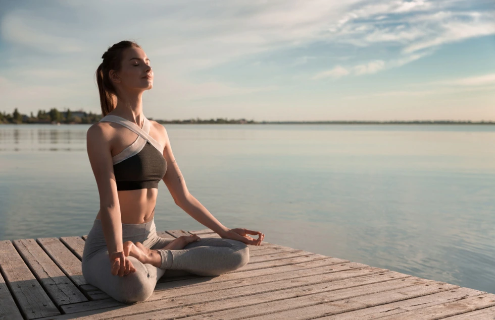 A woman meditating near a river bank 