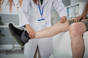 Physiotherapist checking hurt leg of senior man